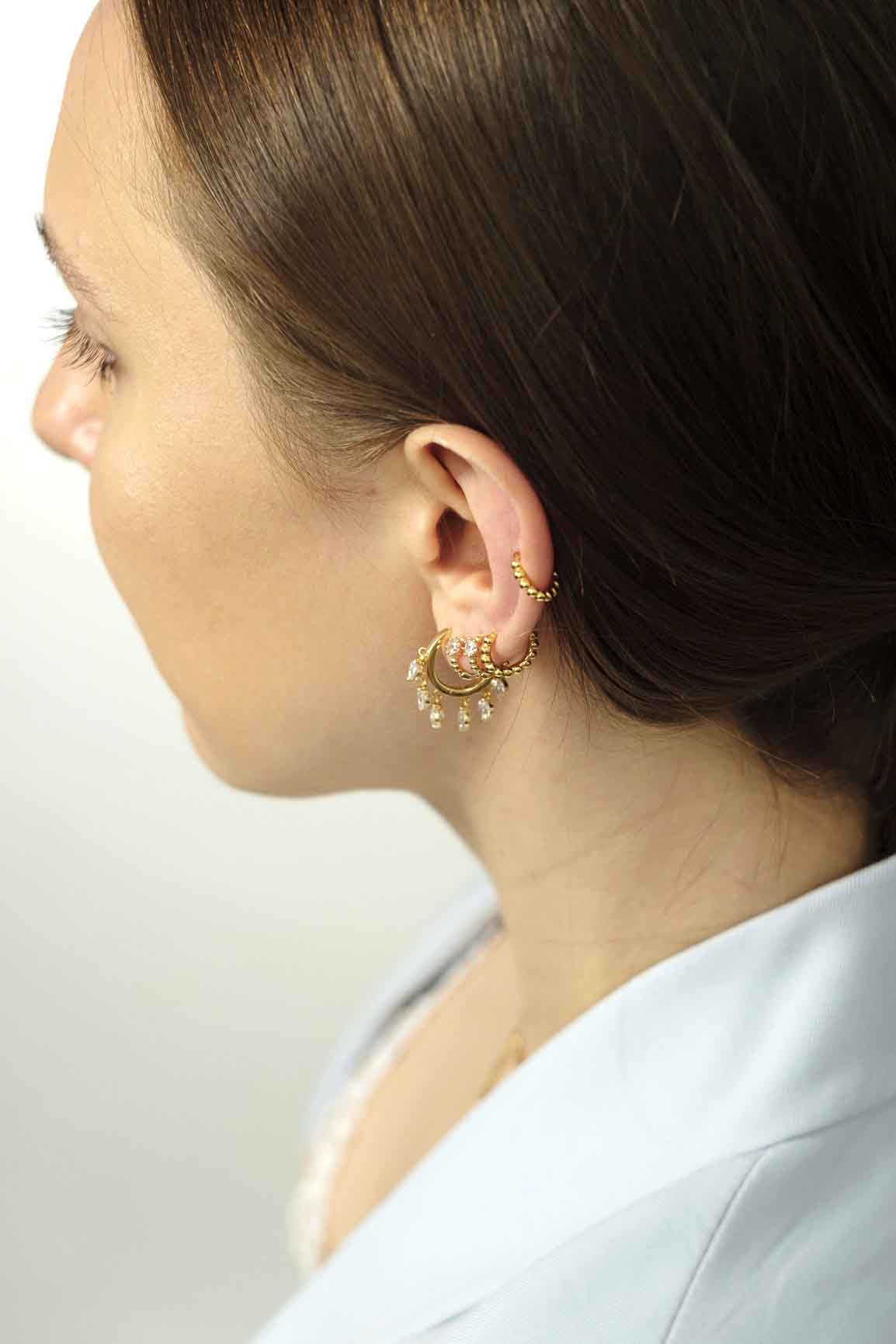 Young lady with ear piercings. Gold piercings earrings.
